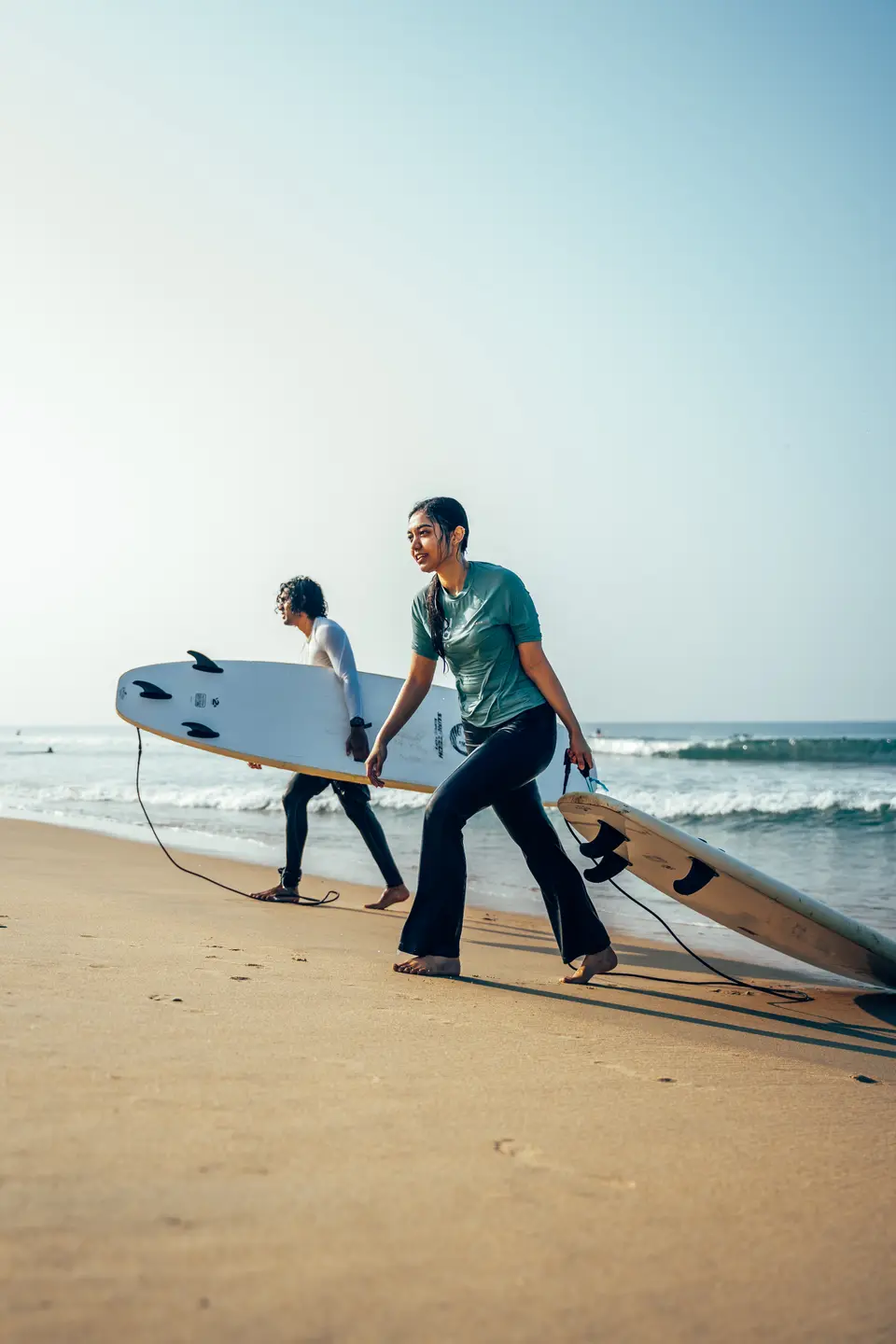 An instructor walking a student and their boards down to the water at Edava