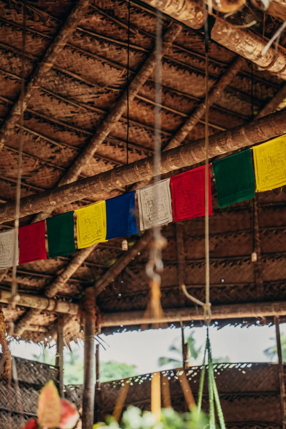 Coloured flags strung along a beam under the palm-leaf roof