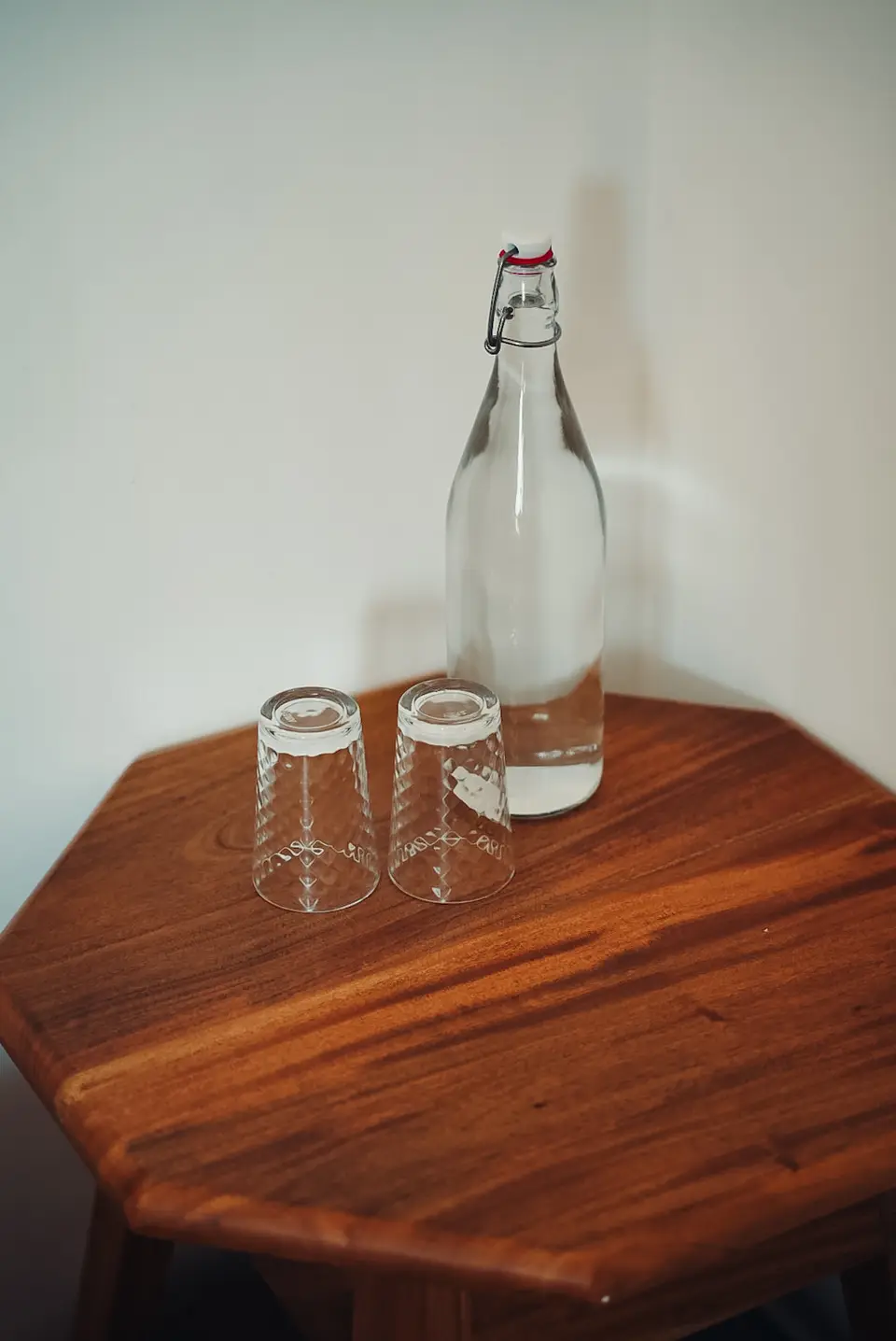 A filtered water carafe and glasses on a teak side table