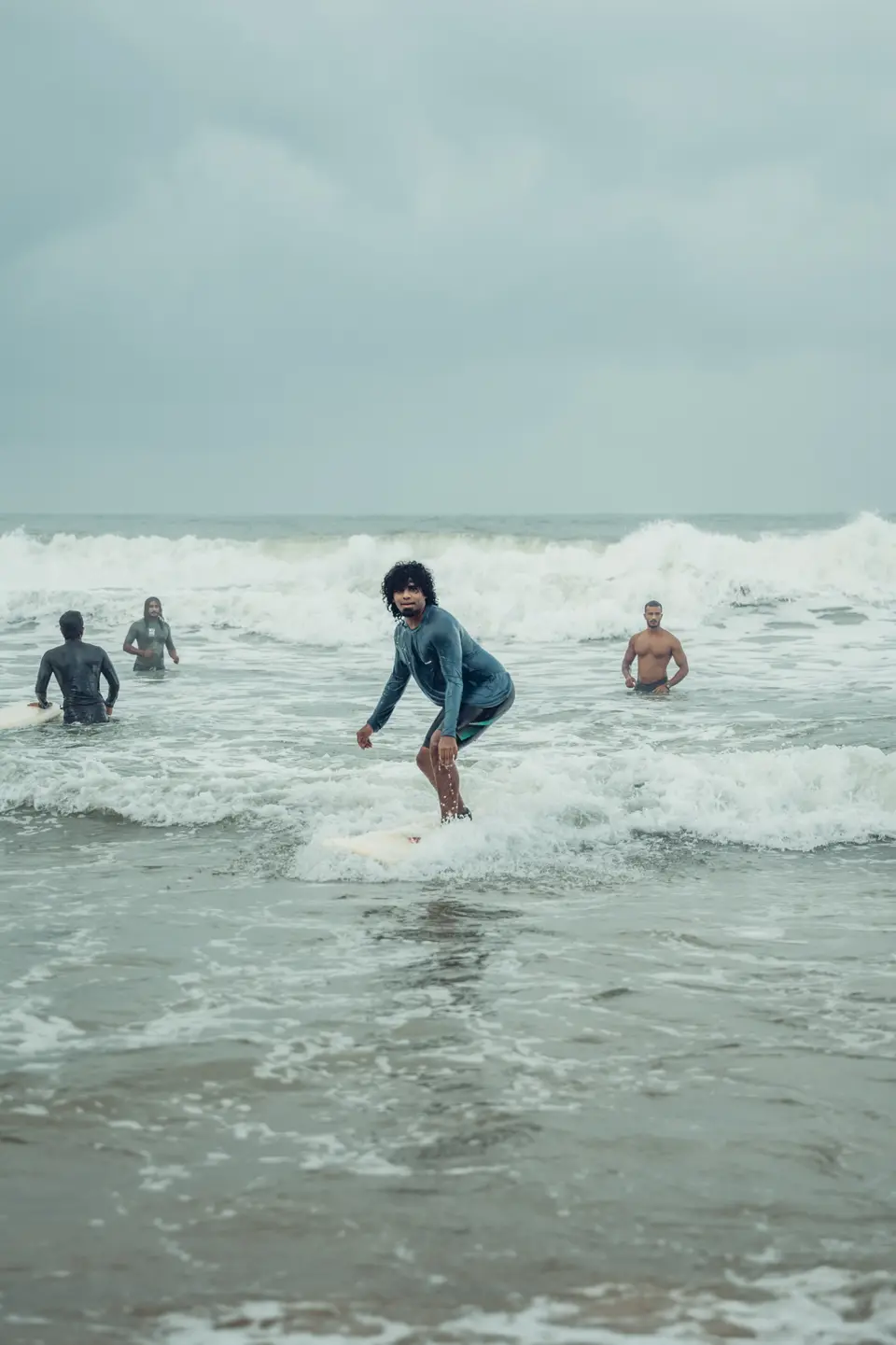 Crouched on a board in the whitewash, three more people in the water behind
