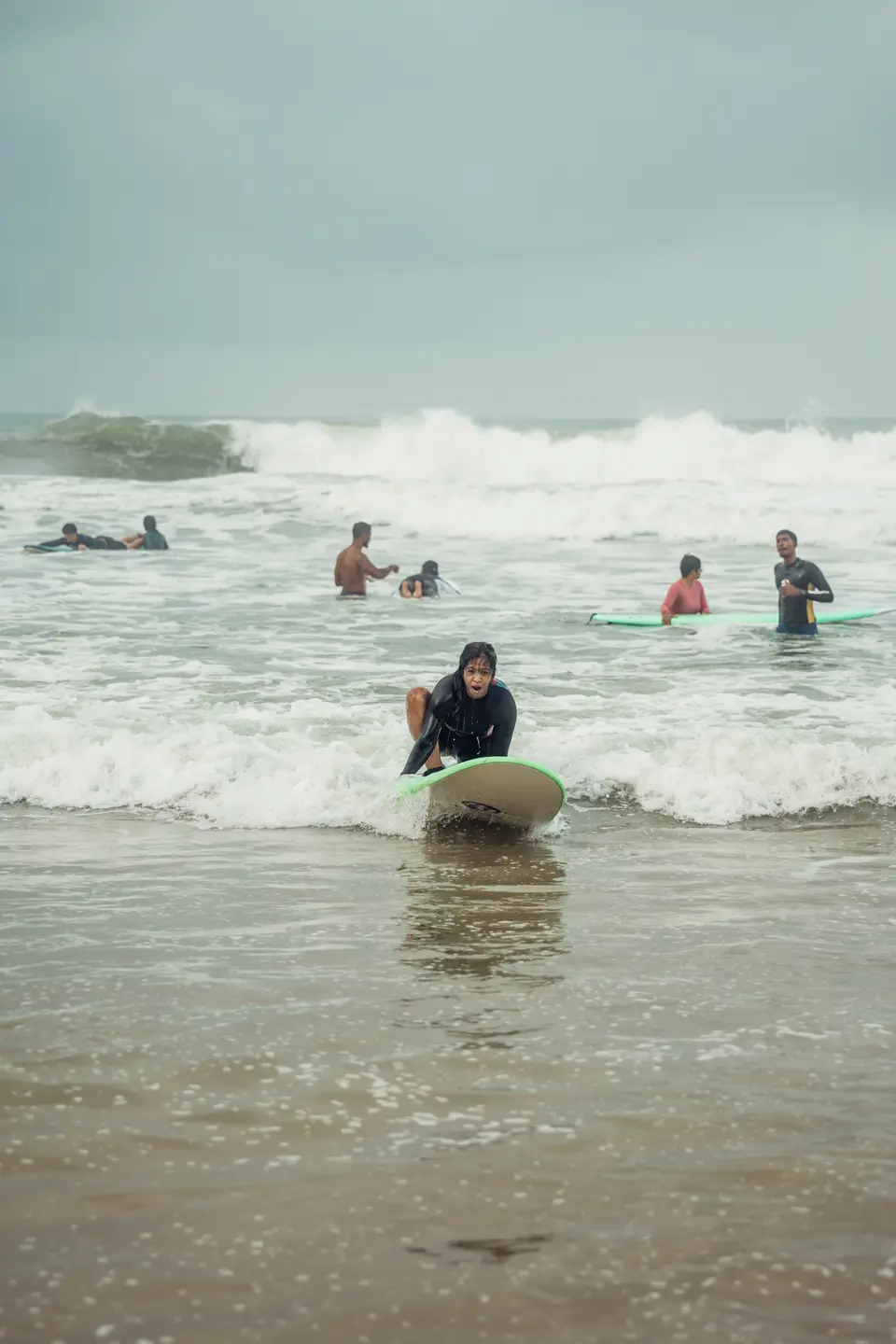 Riding the whitewash in on a green-railed board, more people and boards out behind