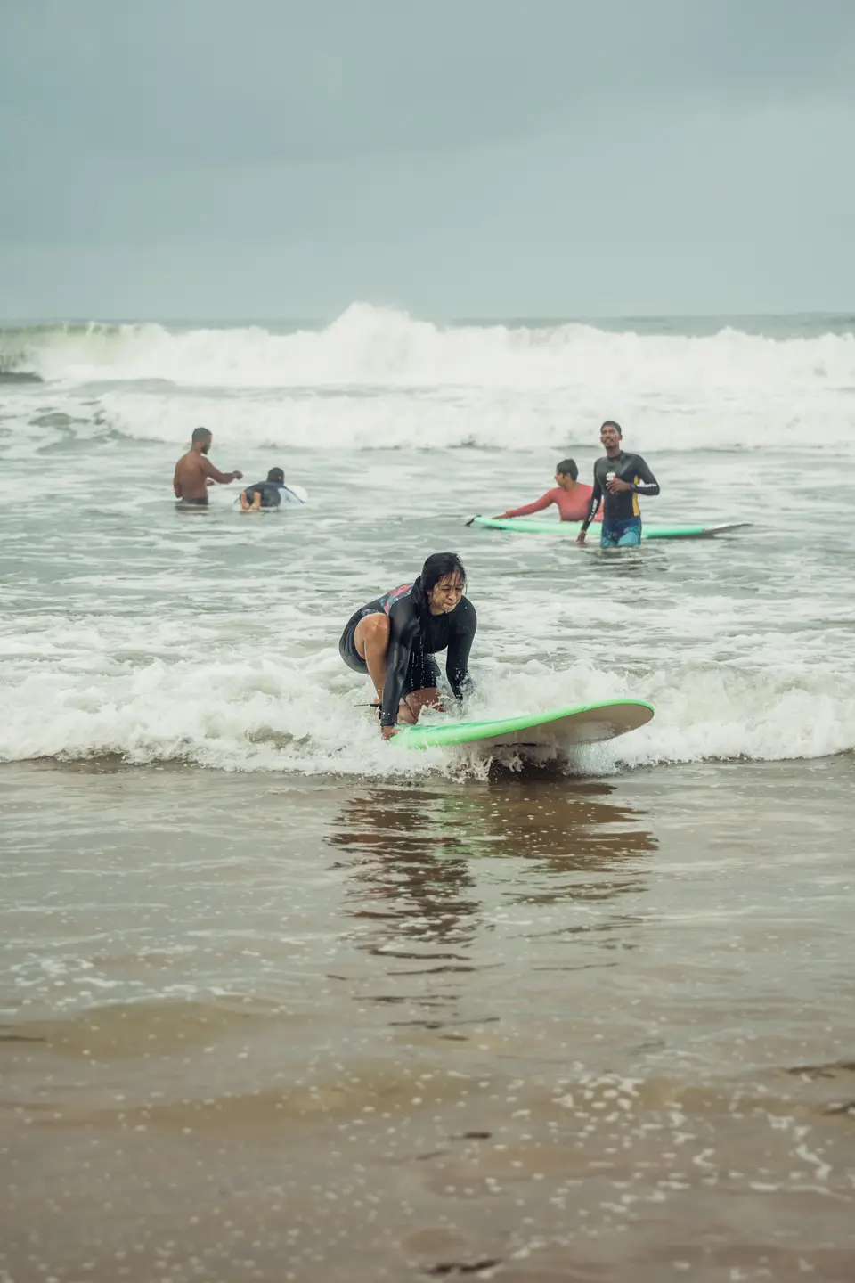 A woman crouching low on a board in shallow whitewash
