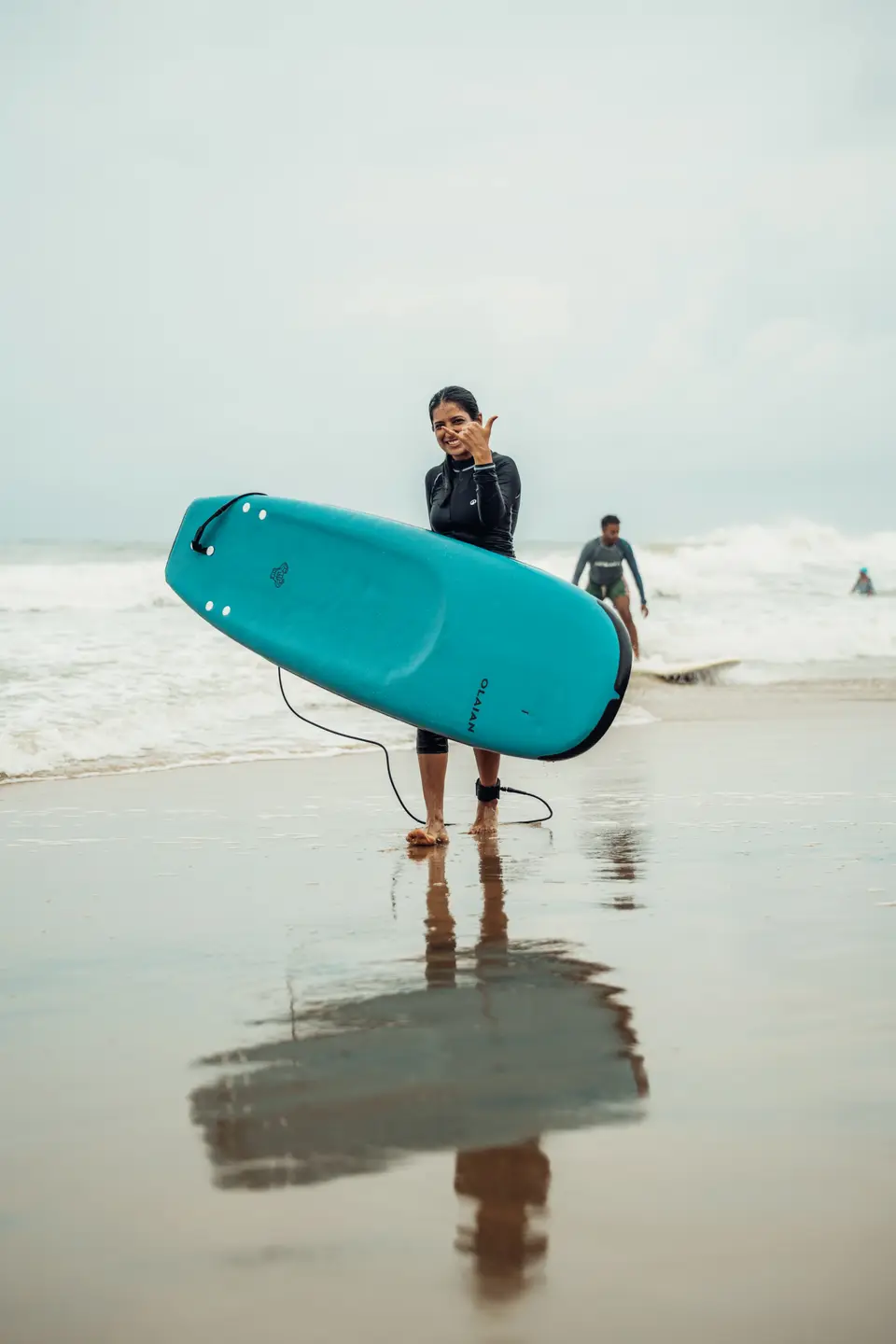 Carrying a soft-top surfboard out of the water at Edava beach