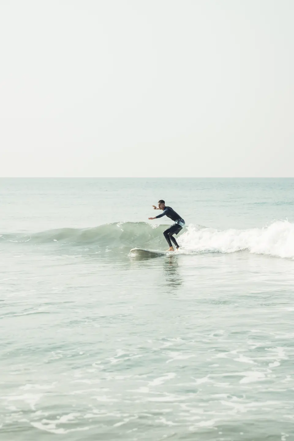 A clean small wave at Edava with a surfer riding across it