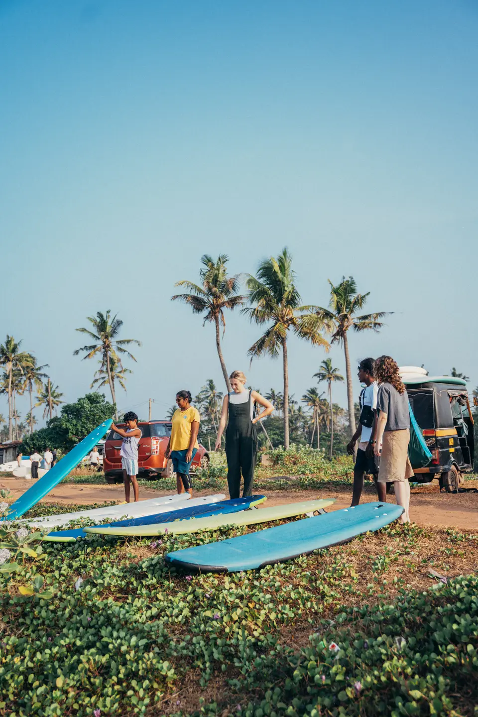 A group gathered with surfboards on the grass under palm trees